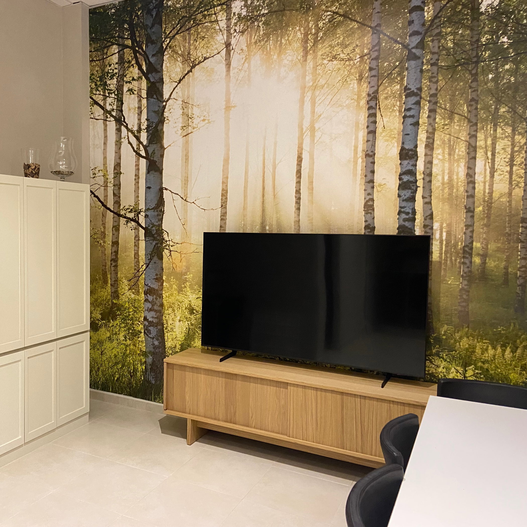 Modern living room with birch tree wallpaper, TV, and wood media console.