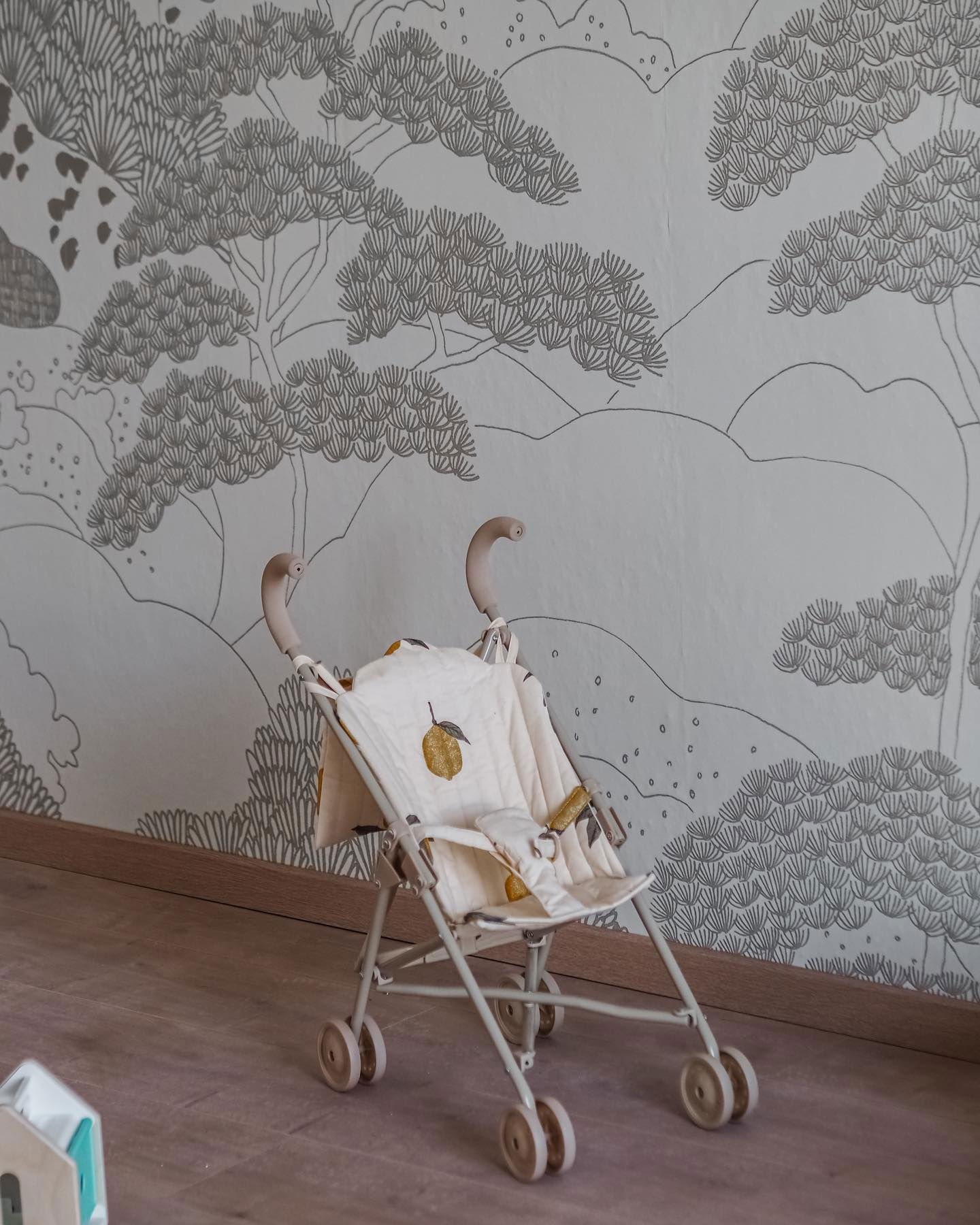 Leksaksvagn med citrontryck på sitsen, mot tapet med träd- och bergsdesign.