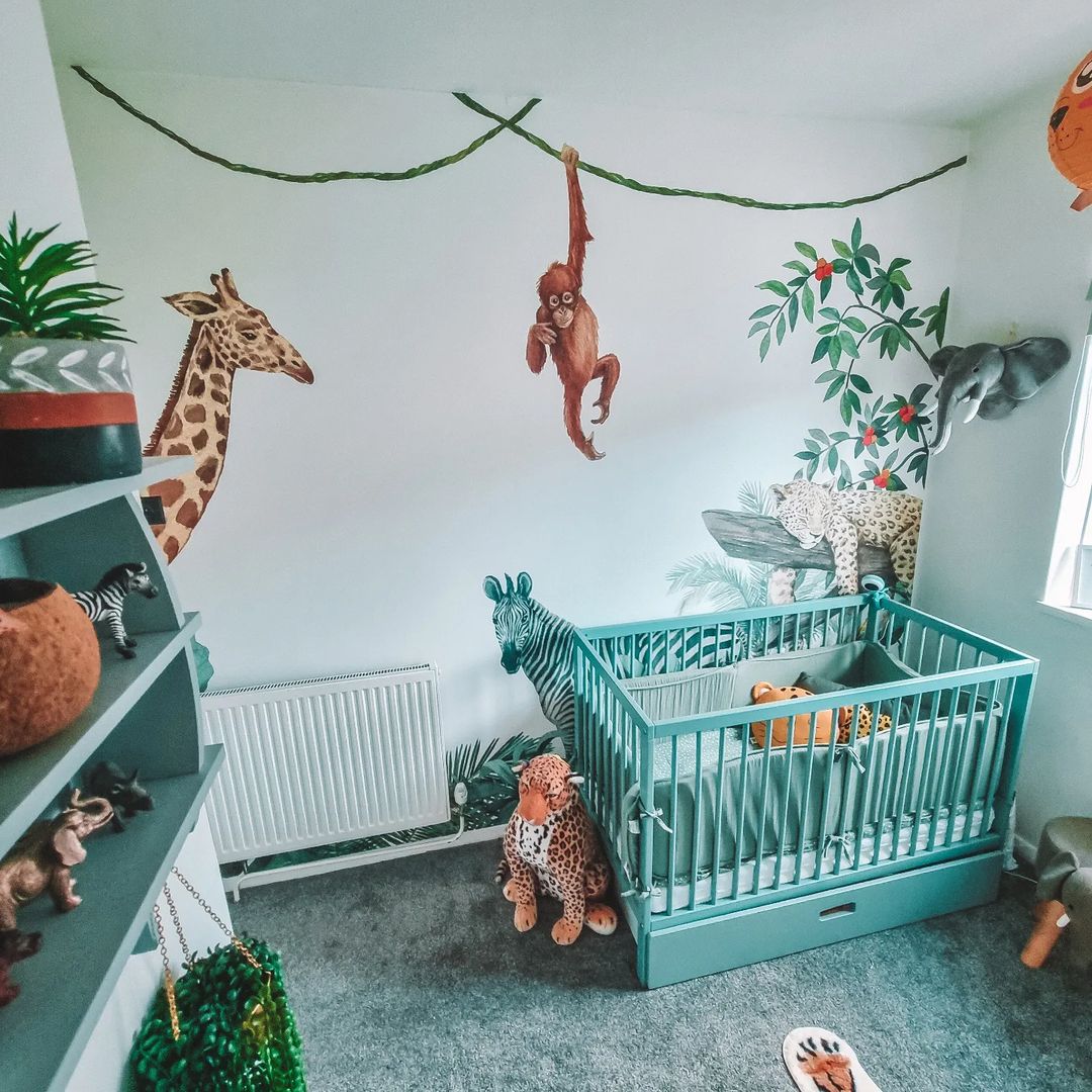 Nursery with blue crib, jungle animal wall decals, and stuffed animals.