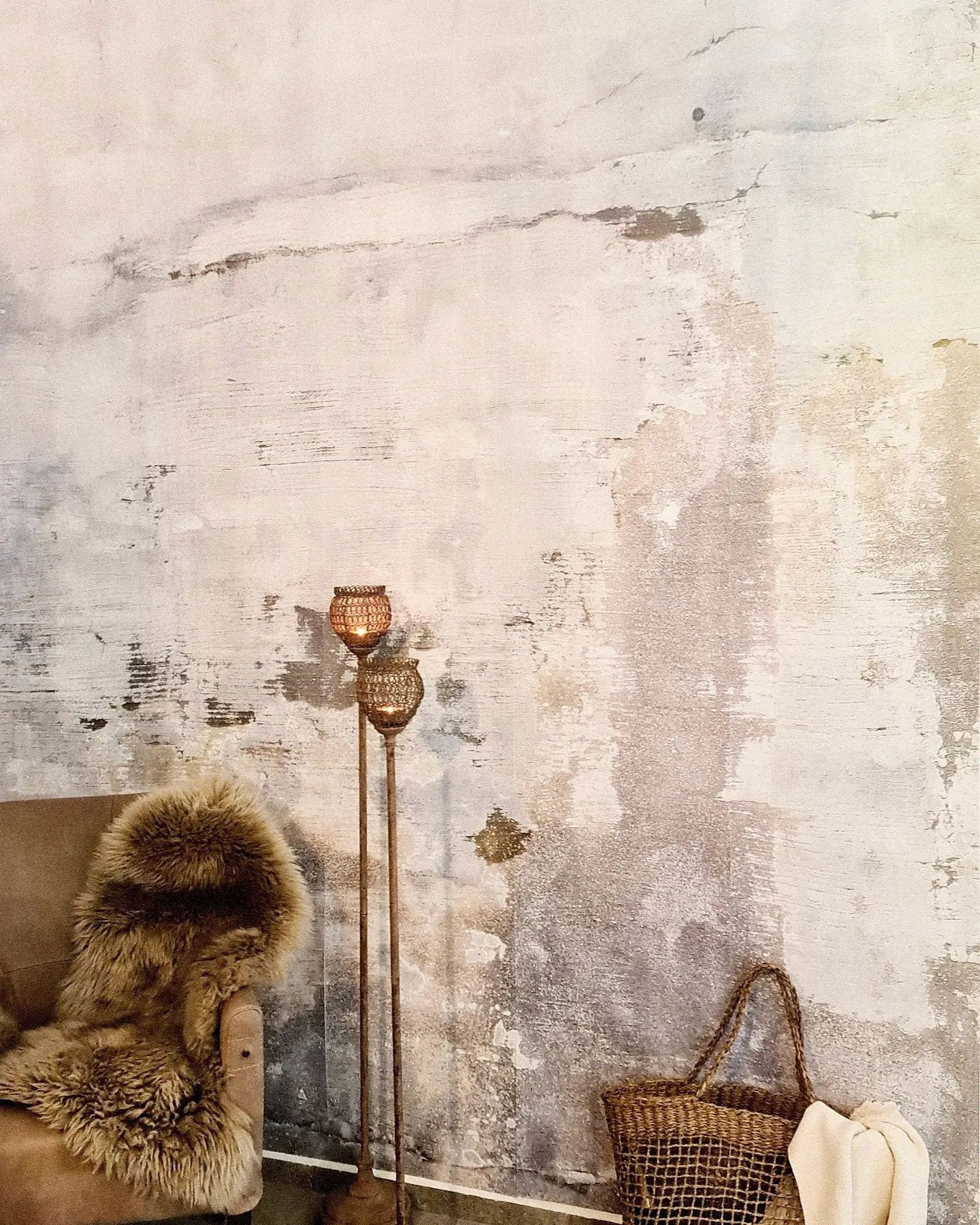 Gezellig interieur met getextureerde muur, stoel met vachtkleed, geweven mand en kandelaars.
