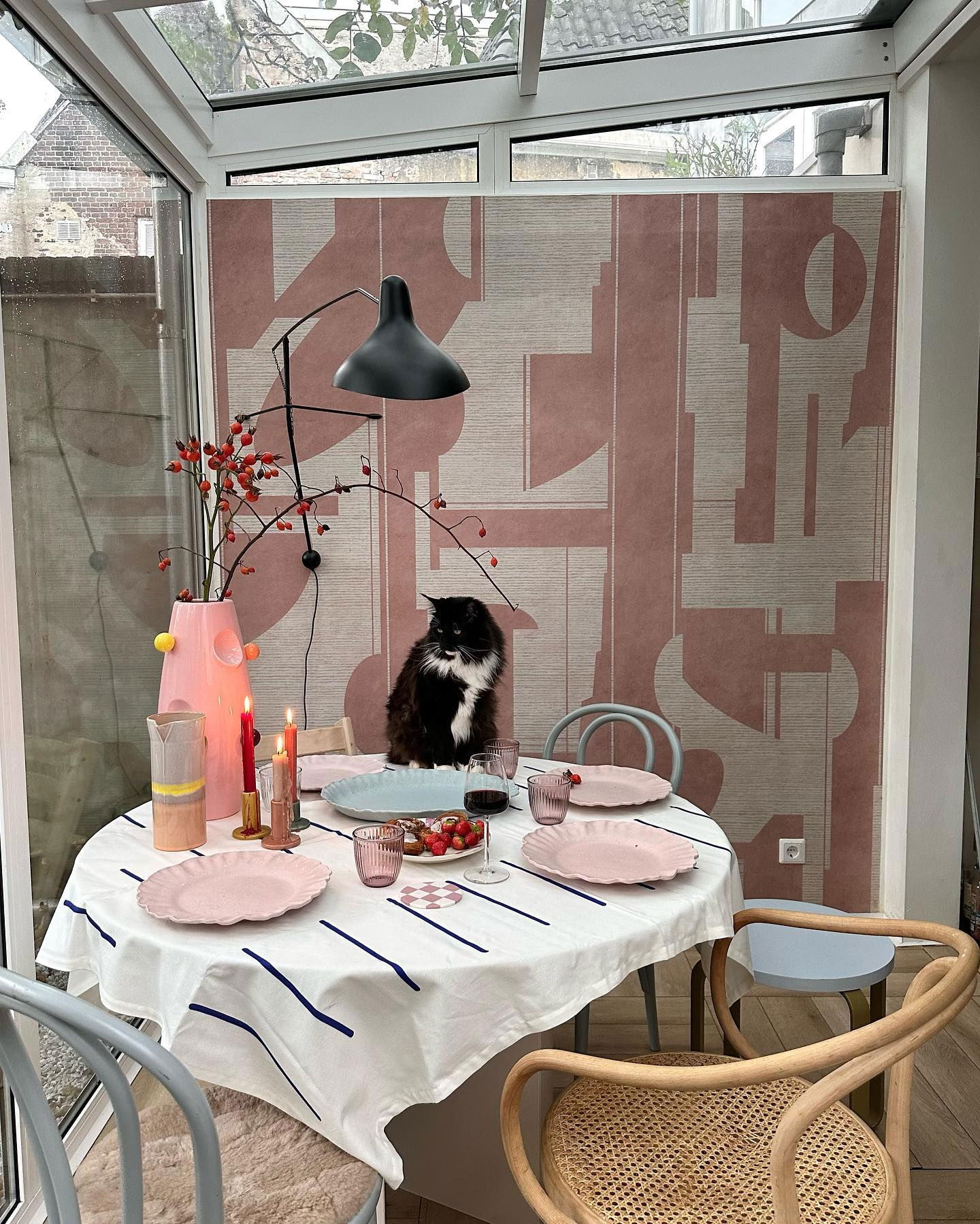 Esszimmer mit rundem Tisch für eine Mahlzeit gedeckt, Katze sitzt am Tisch.