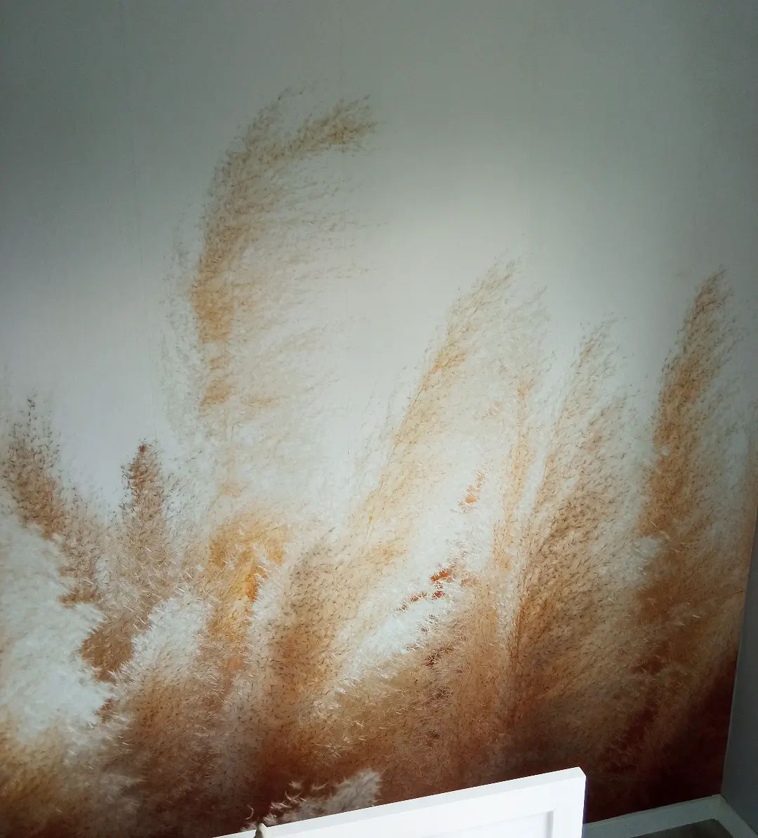 Primer plano de una pared con un diseño de hierba de la pampa en marrón y blanco.