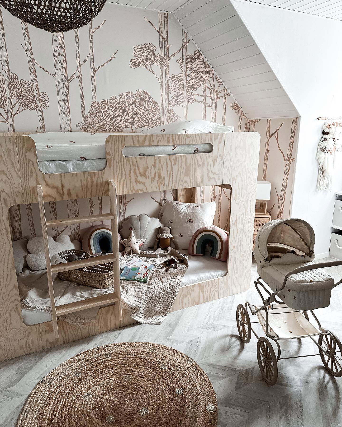 Child's room with wooden bunk bed, forest wallpaper, woven rug, and vintage-style doll stroller.