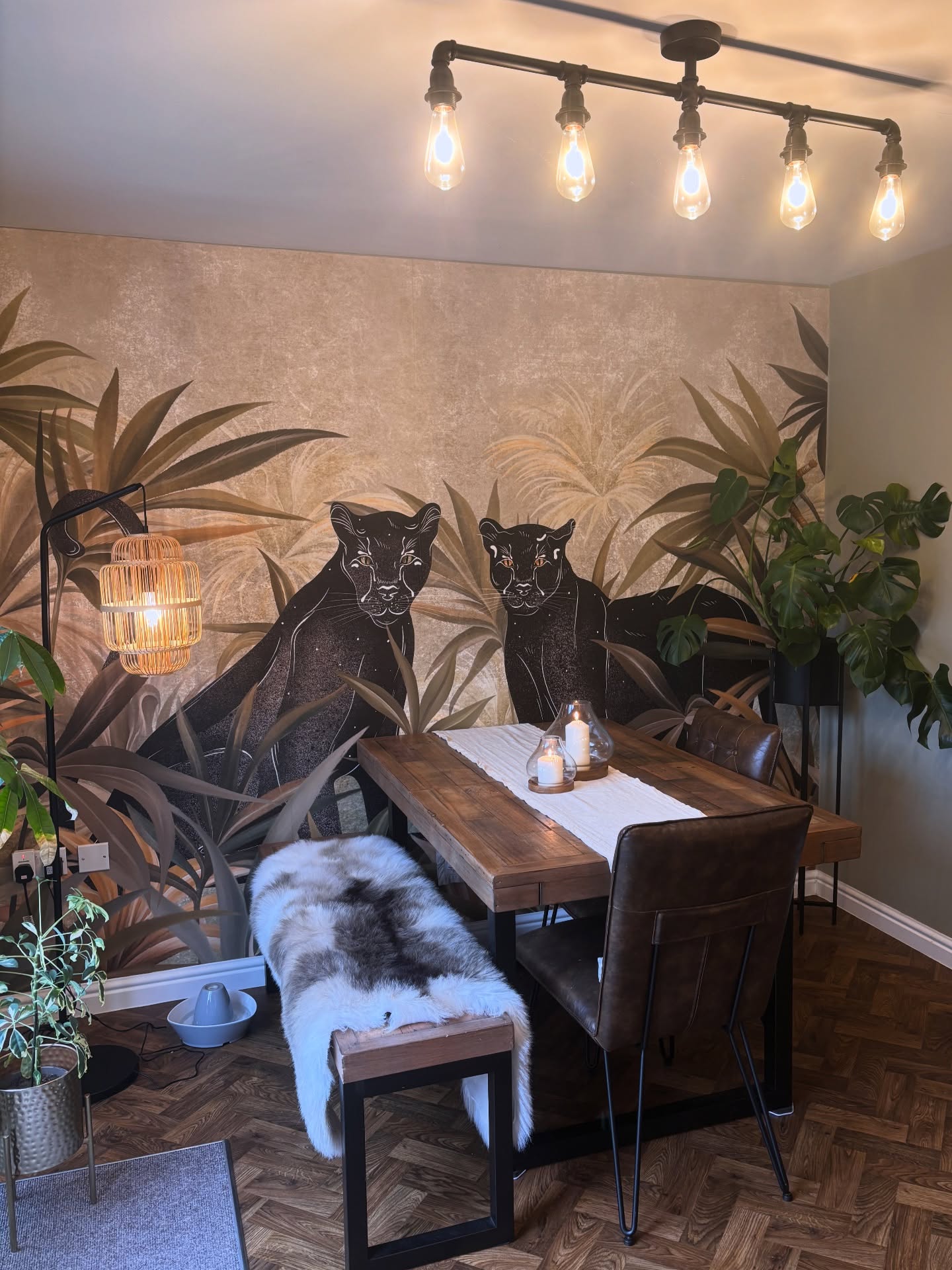 Dining room with jungle mural, wood table, and leather chairs.