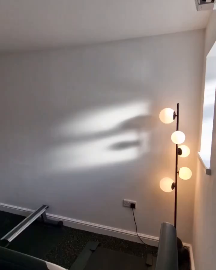 Interior view of a room with a modern globe floor lamp and exercise equipment.