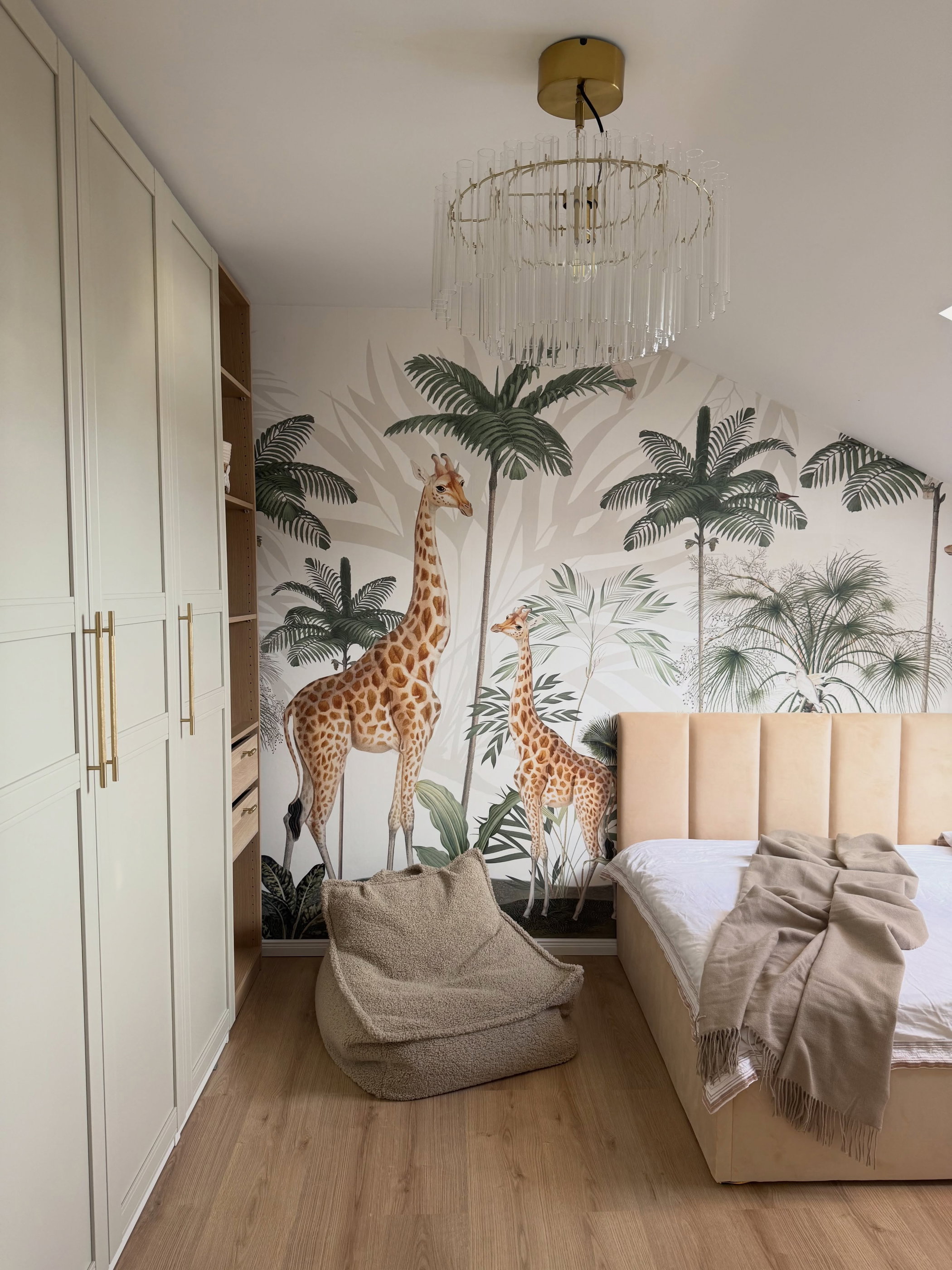 Bedroom with giraffe mural, tan bed, and bean bag chair.