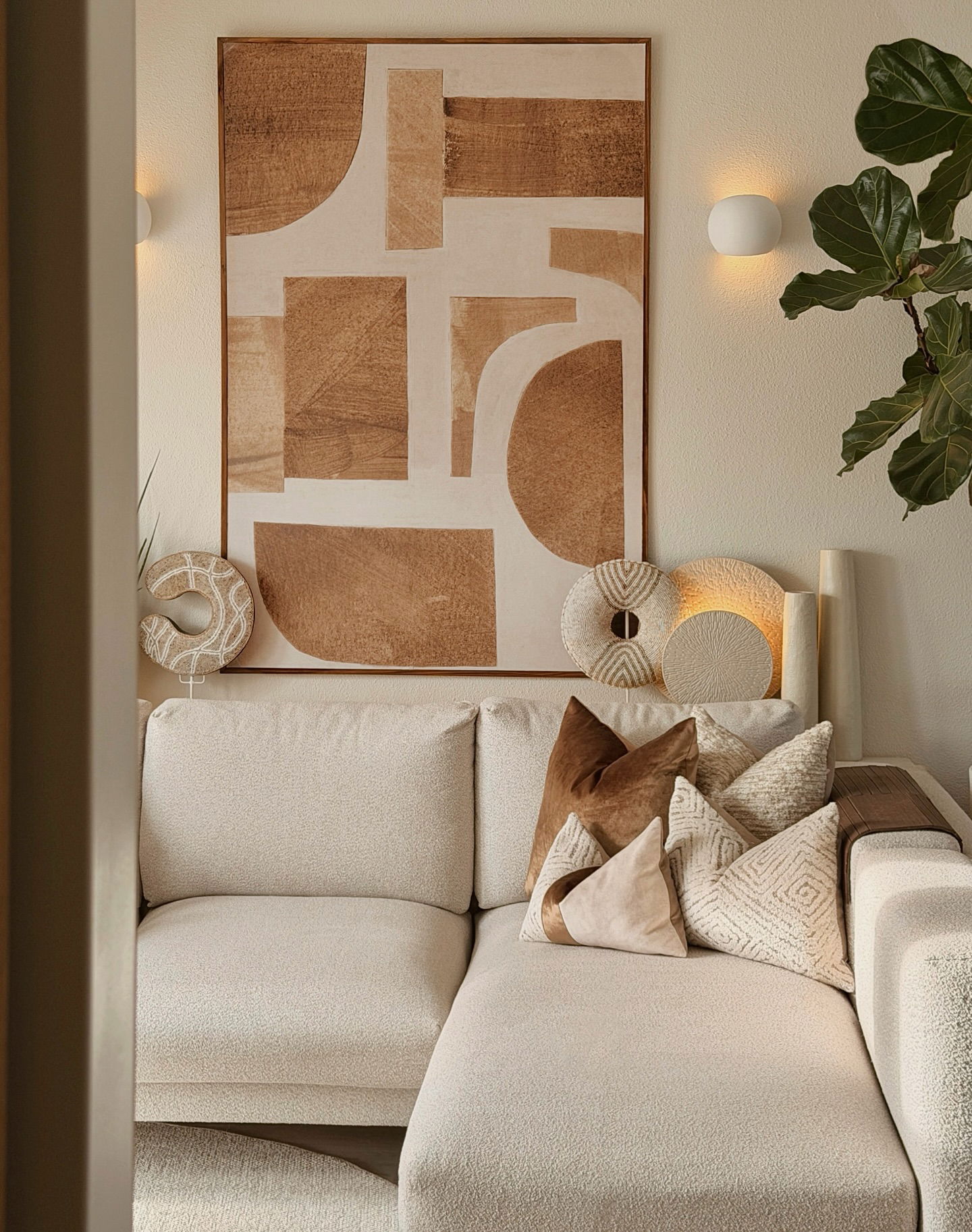 Cream sectional sofa with textured pillows and an abstract art print above.