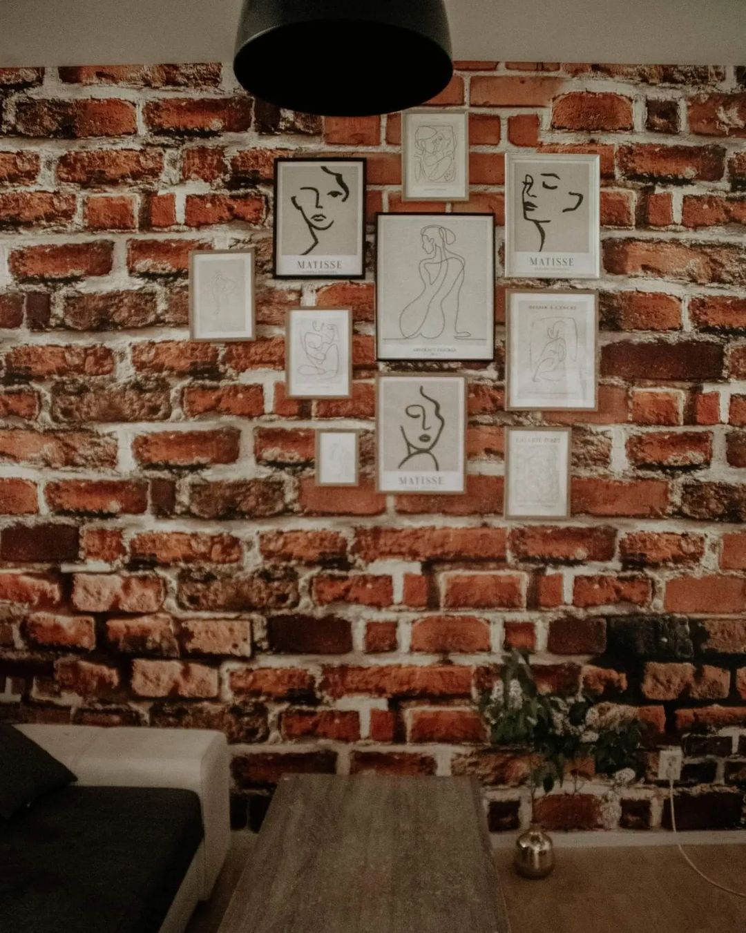 Living room with brick wall, Matisse art prints, sofa, and coffee table.