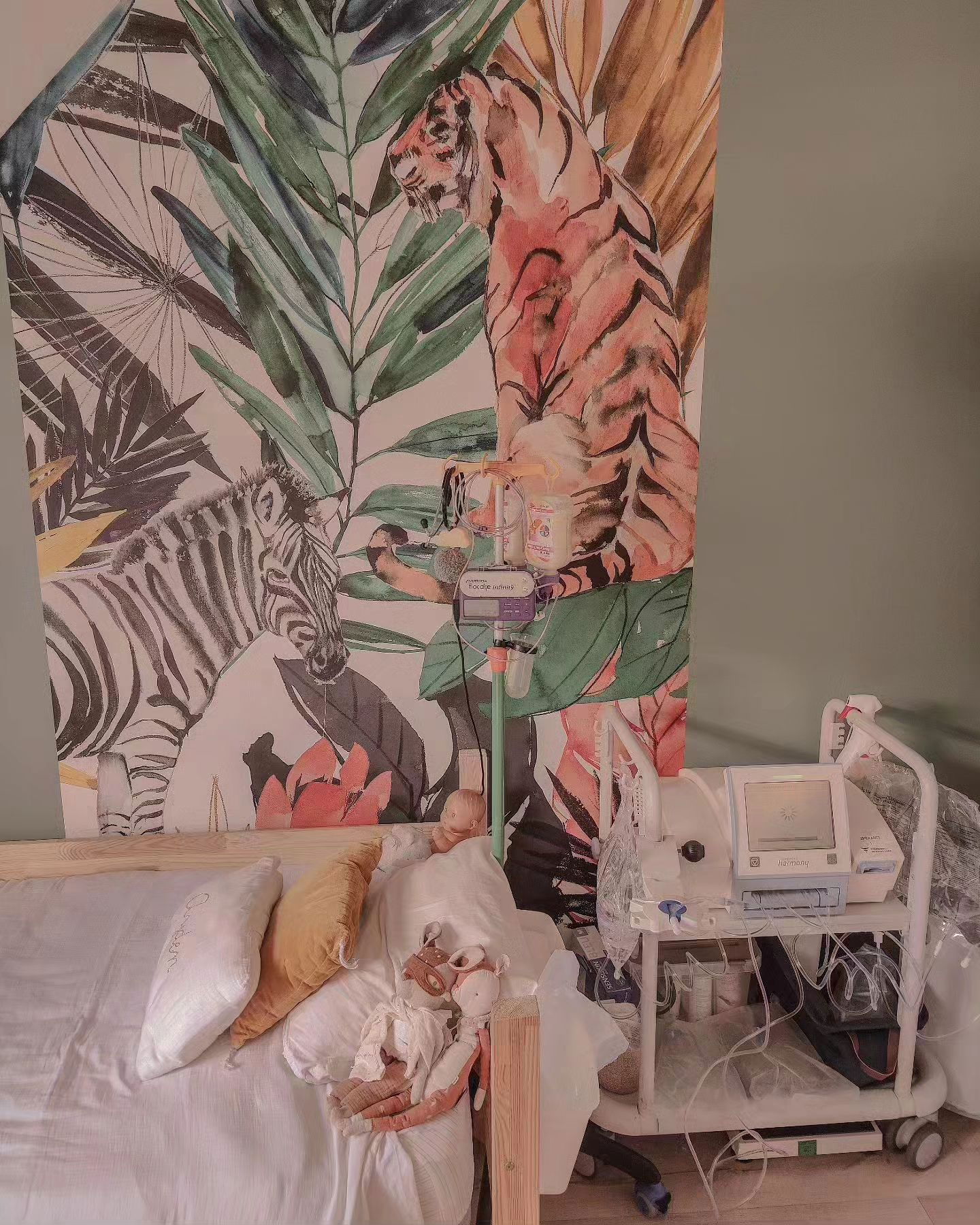 Niño en la cama con equipo médico, papel tapiz de animales de la jungla detrás.