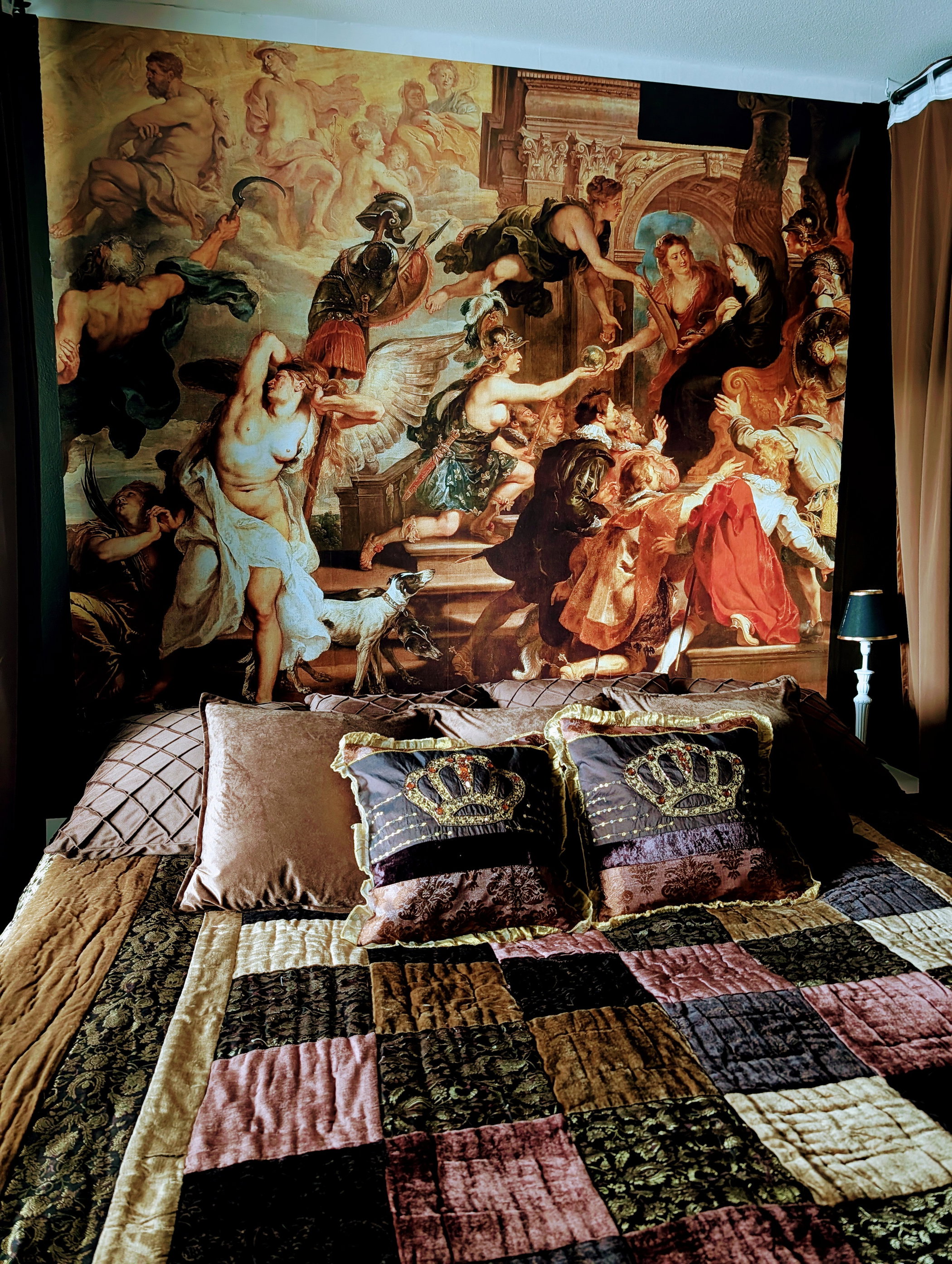 Bed with a Baroque tapestry and decorative pillows with crowns.