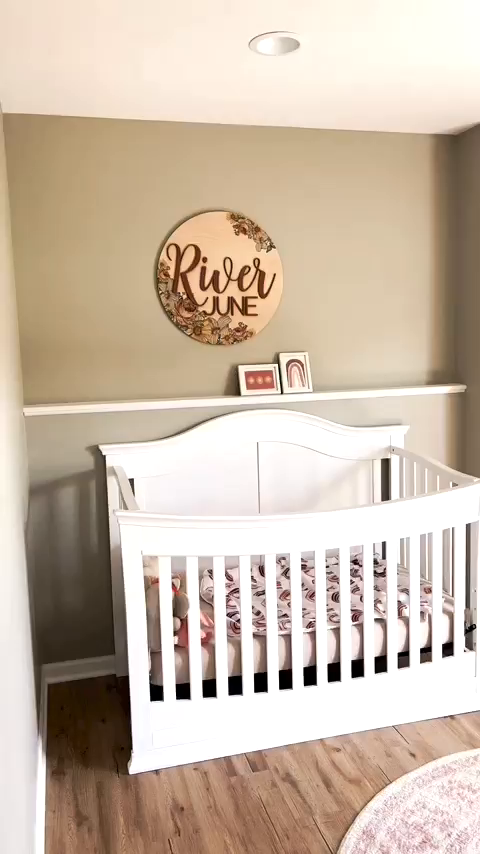Nursery with white crib, floral bedding, and "River June" name sign.