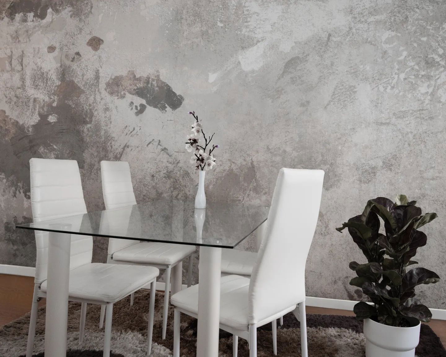 Dining room with glass table, white chairs, and textured gray wall.