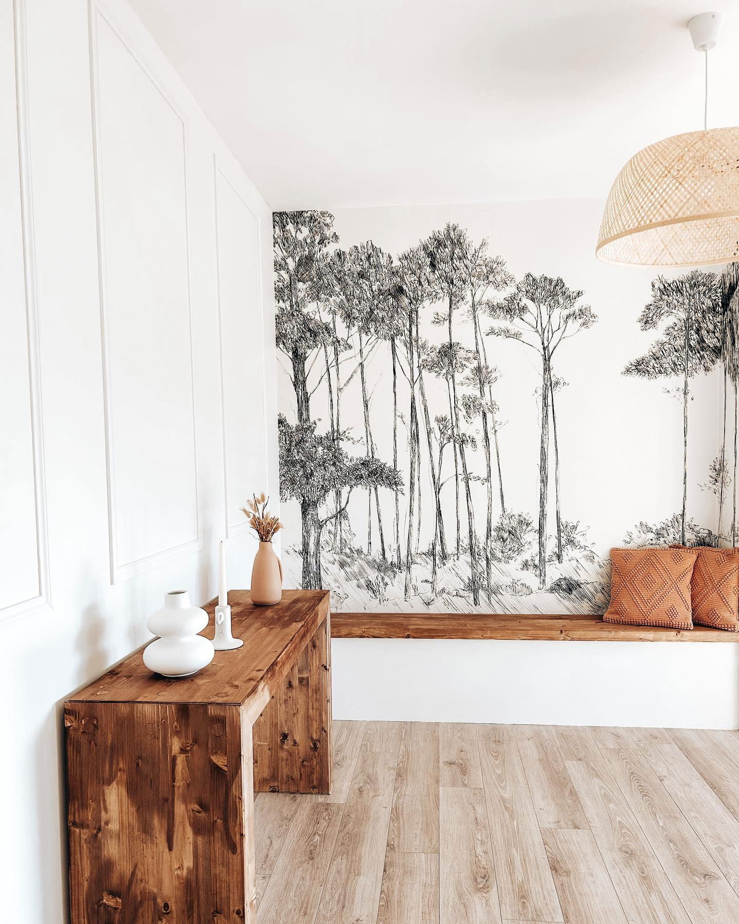 Minimalistischer Raum mit Holzböden, Konsolentisch, Bank und Waldwandbild.