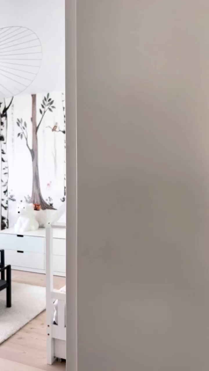 A peek into a child's room with forest-themed wallpaper.