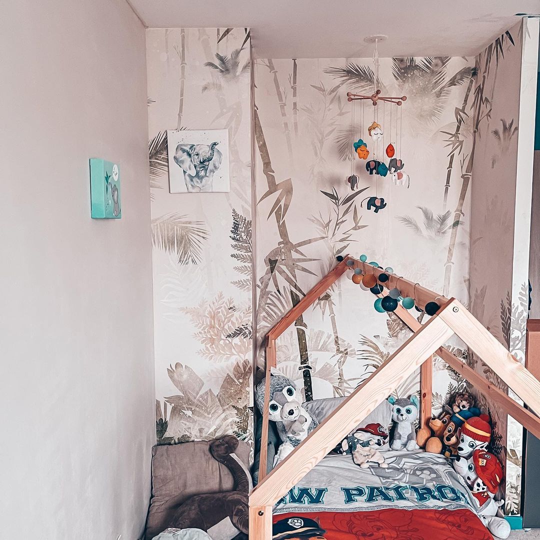 Child's bedroom with jungle wallpaper, house frame bed, and Paw Patrol bedding.