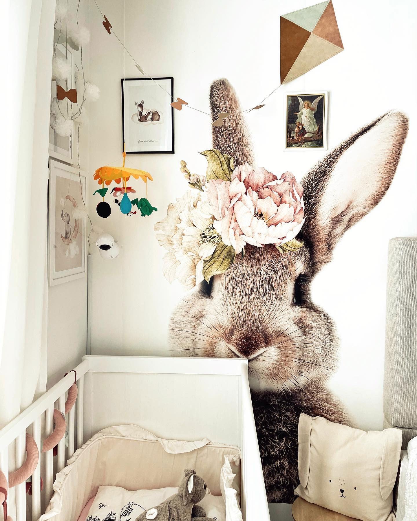 Nursery with white crib, bunny wall decal with floral crown, and animal-themed decor.