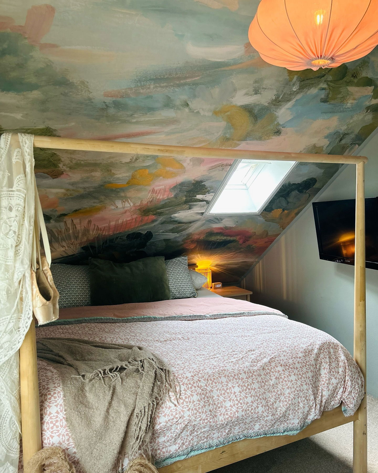 Schlafzimmer mit Himmelbett, floraler Bettdecke und gemaltem Deckengemälde.