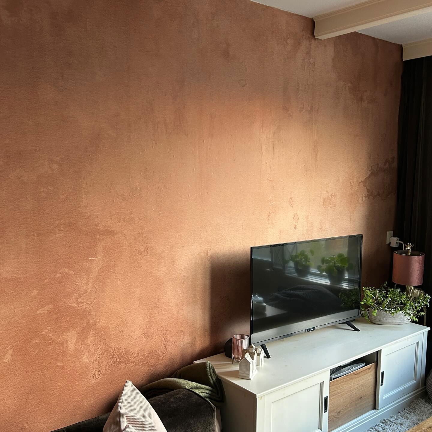 Living room with textured copper-colored wall, white media console, and TV.