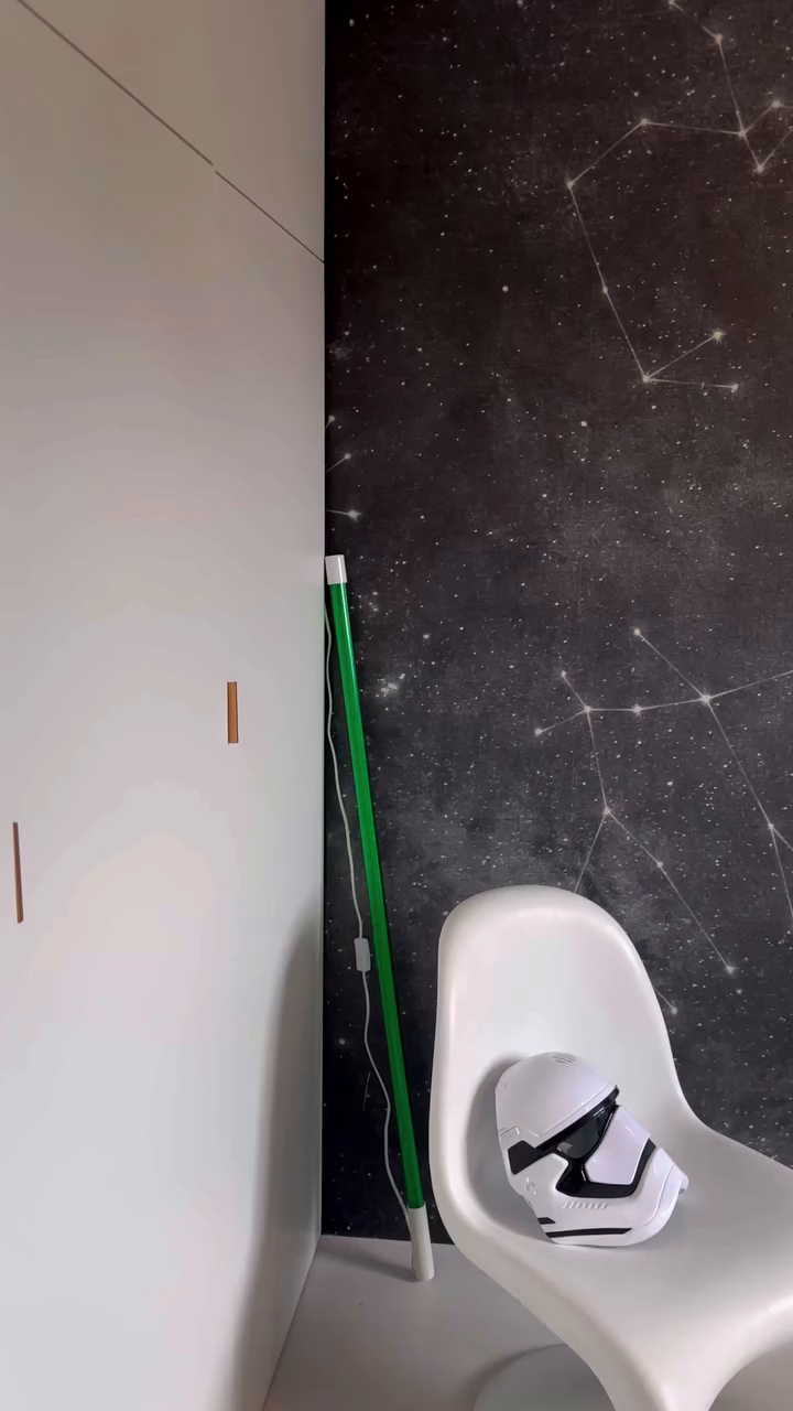 Star Wars First Order stormtrooper helmet on a white chair, next to a green light.