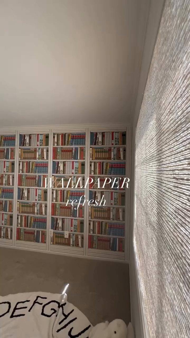 Room with bookcase wallpaper, textured wall, and alphabet rug.