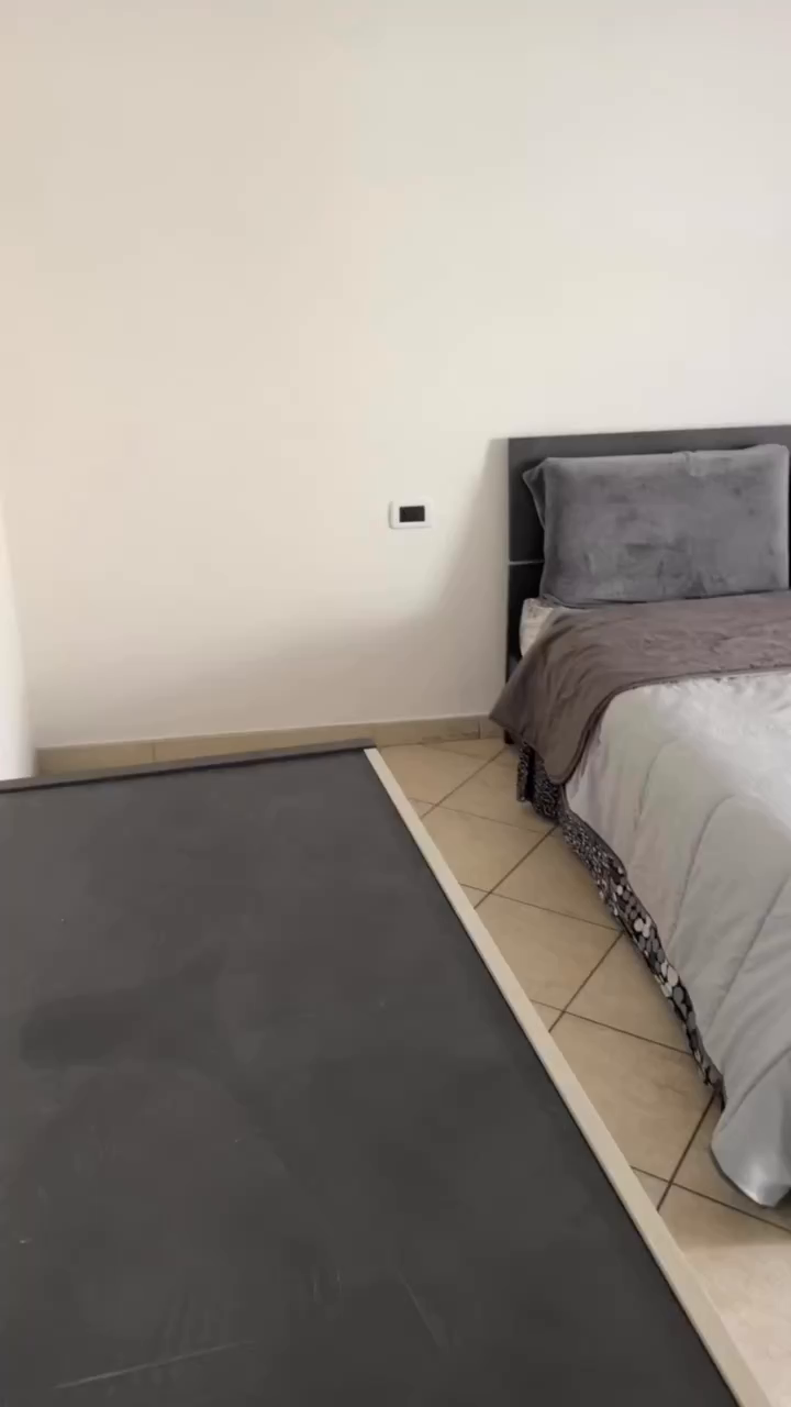 Bedroom with gray bed, headboard, and bedding. Gray floor.