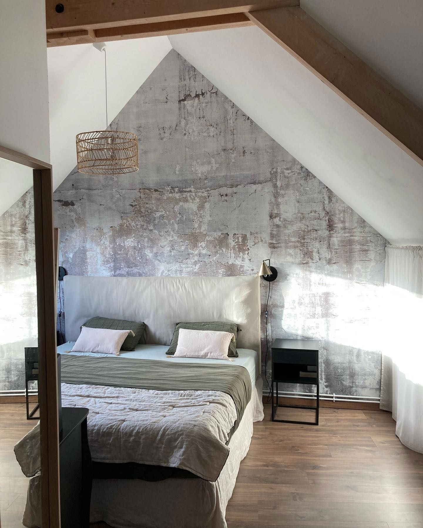 Zolderkamer met getextureerde muur, wit hoofdeinde en geweven hanglamp.
