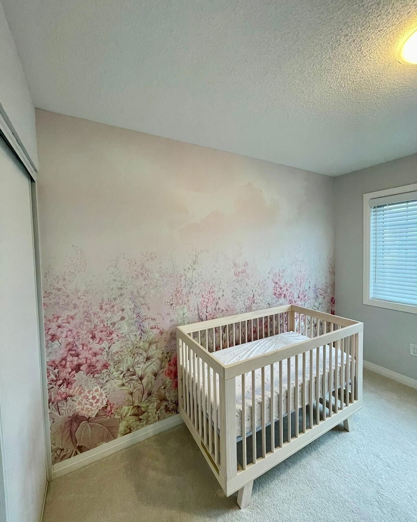 Nursery with floral wallpaper and a modern white crib.