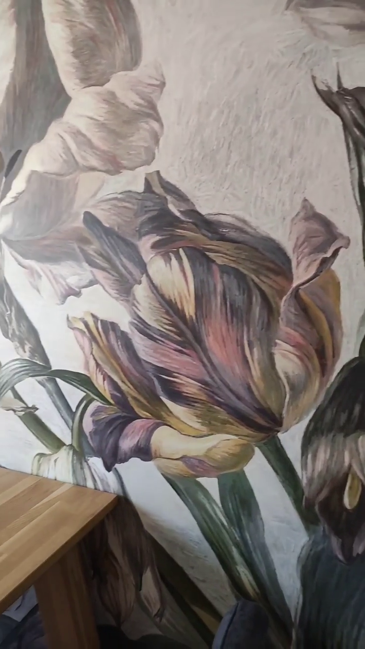 Close-up of a wall with a large floral mural of tulips in purple, pink, and yellow.