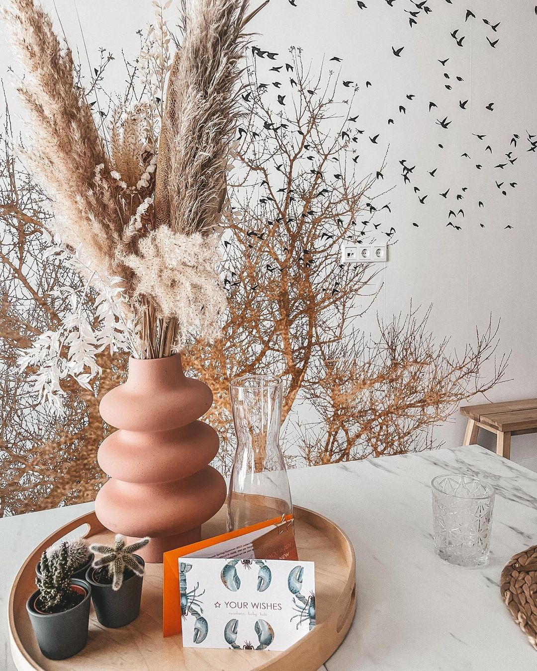 Stilleven met pampasgras in terracotta vaas, cactussen en "Your Wishes" kaart op een houten dienblad.