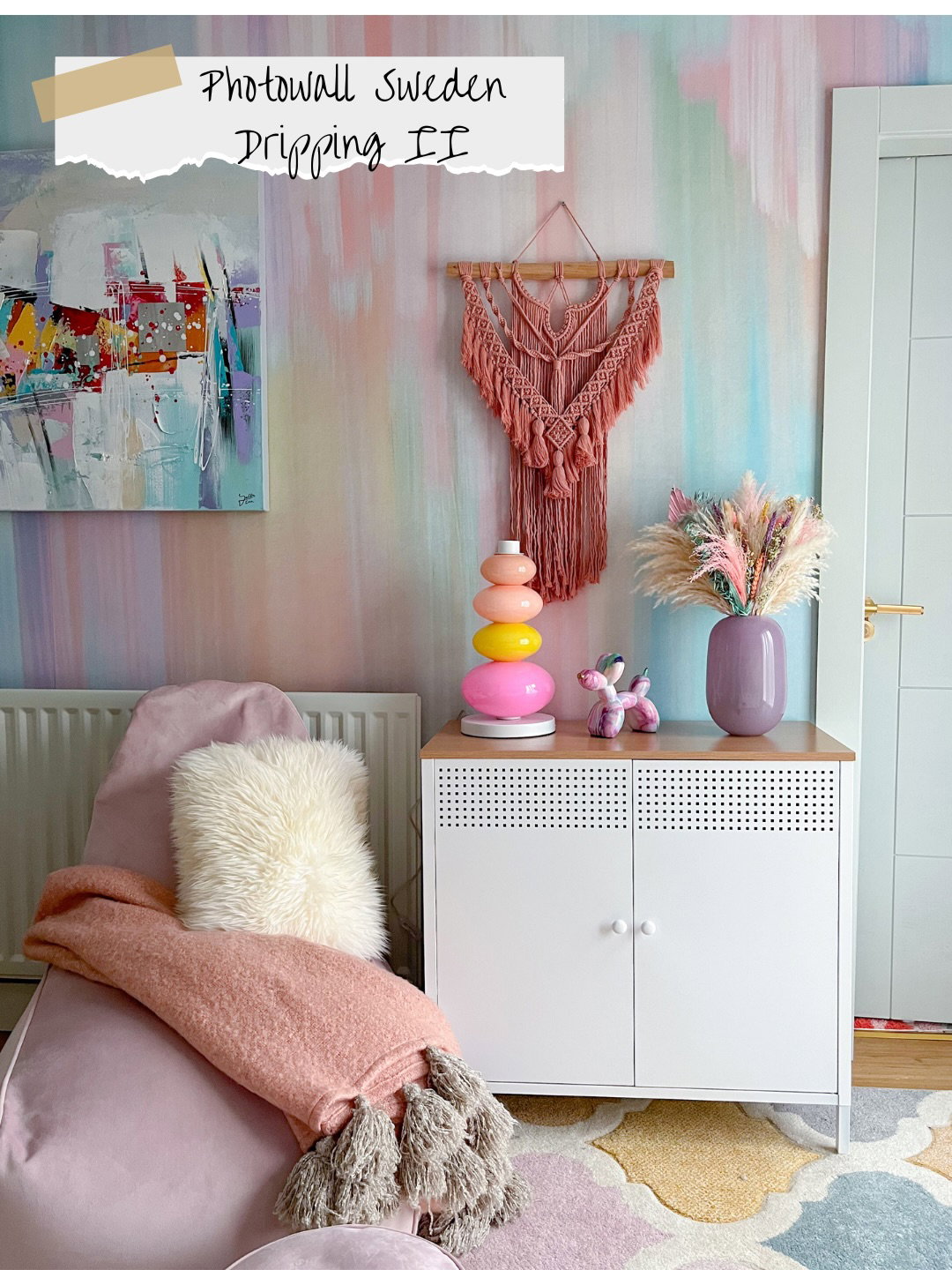 Pastel akvarelvæg med macramé, abstrakt kunst, sækkestol, skab og farverig lampe. Teksten lyder 'Photowall Sweden'.