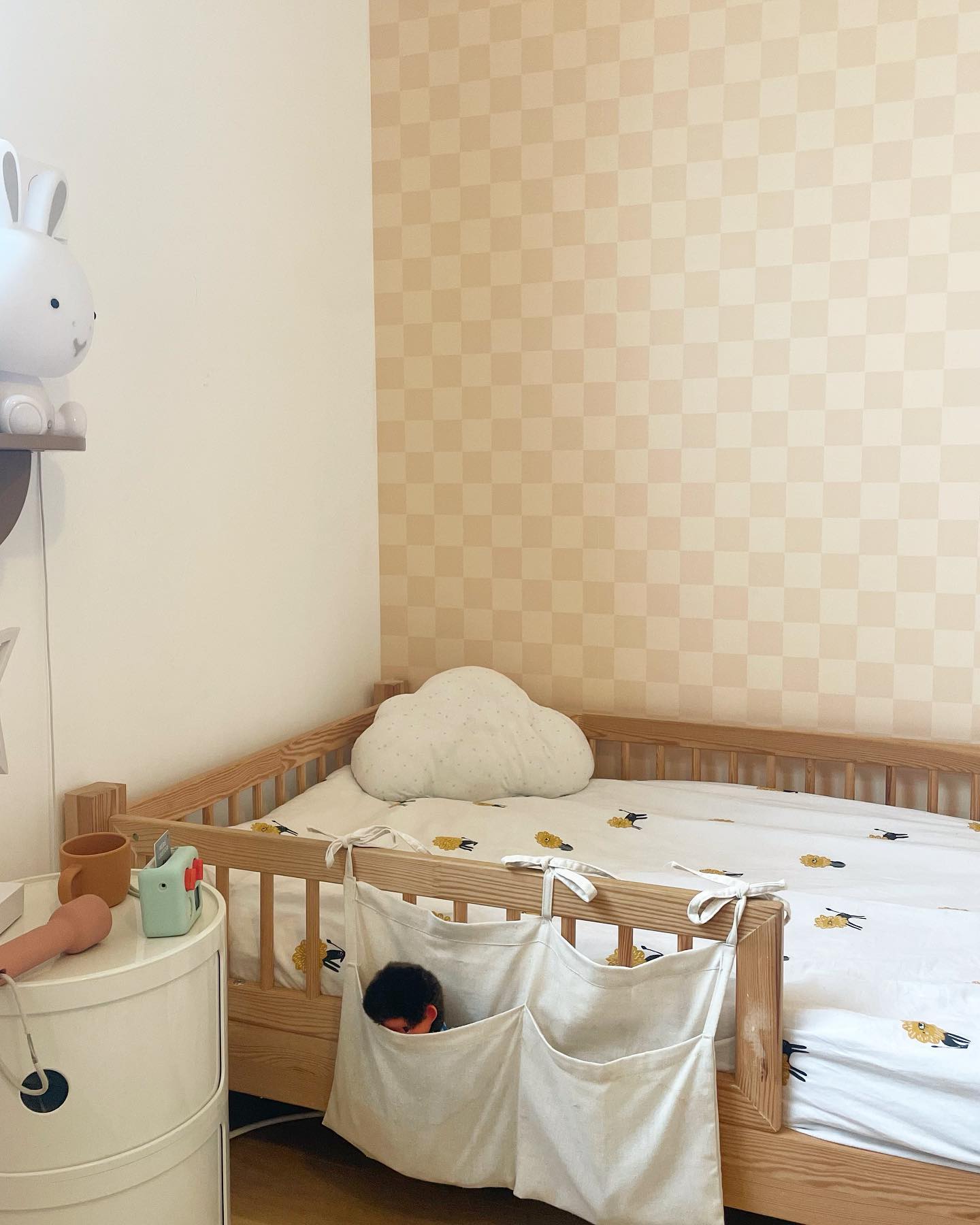 Chambre d'enfant avec lit en bois, oreiller nuage et panier de rangement.