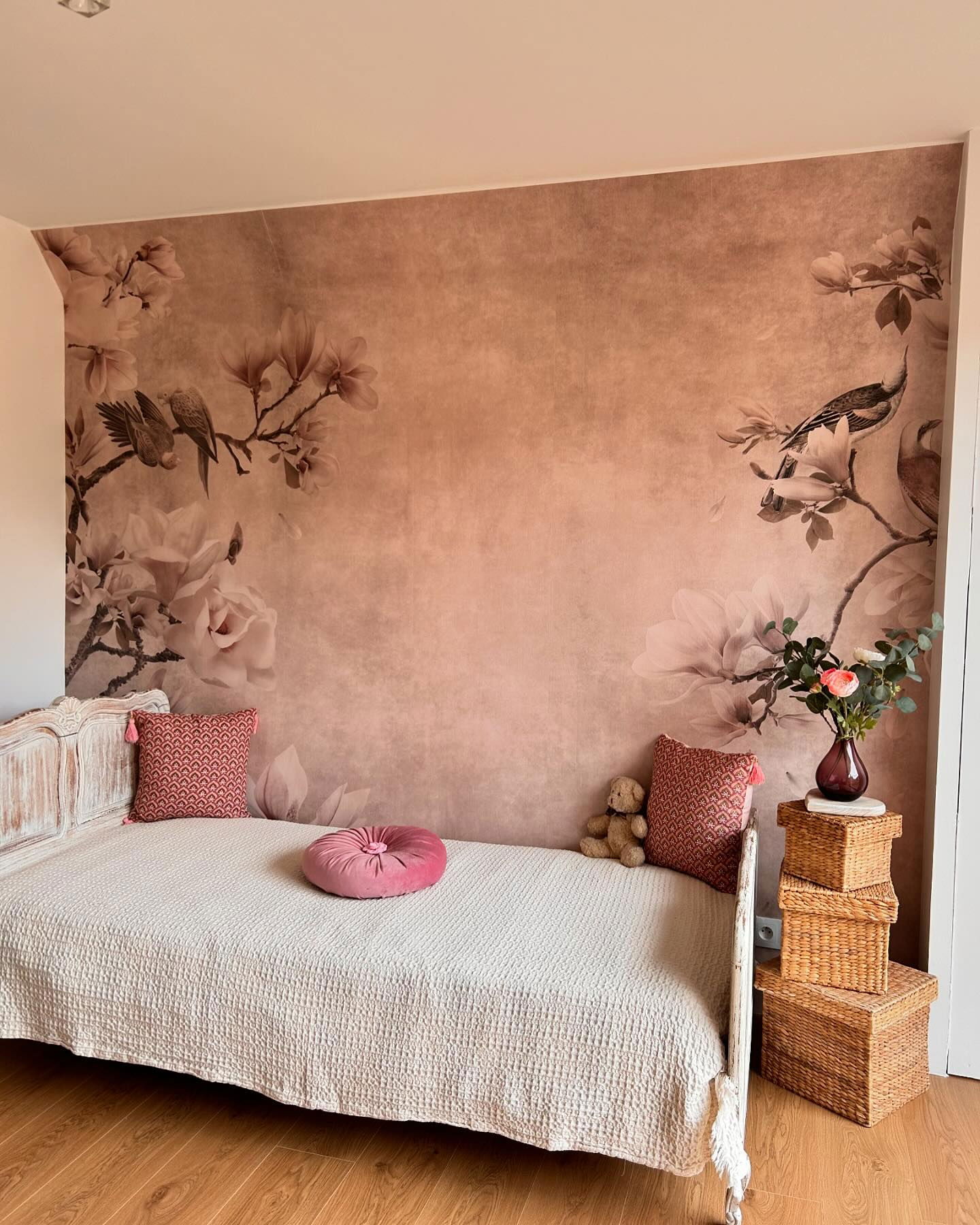 Soverom med blomstrete tapet, divan med teksturert trekk og vevde oppbevaringsbokser.