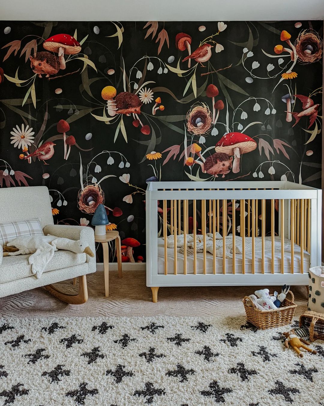 Kinderzimmer mit weißer Wiege, Schaukelstuhl und Pilz-Tapete.