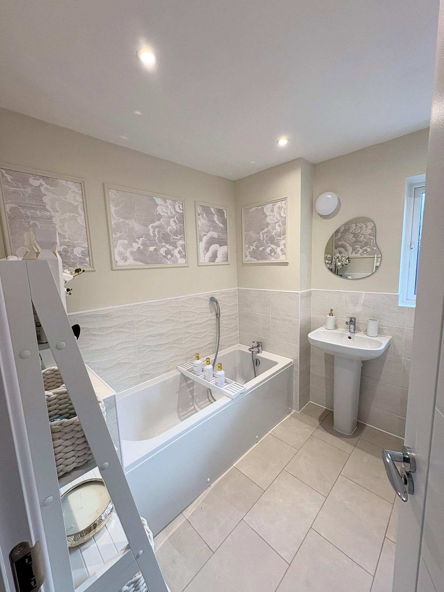 Bathroom with white tub, pedestal sink, and cloud art.