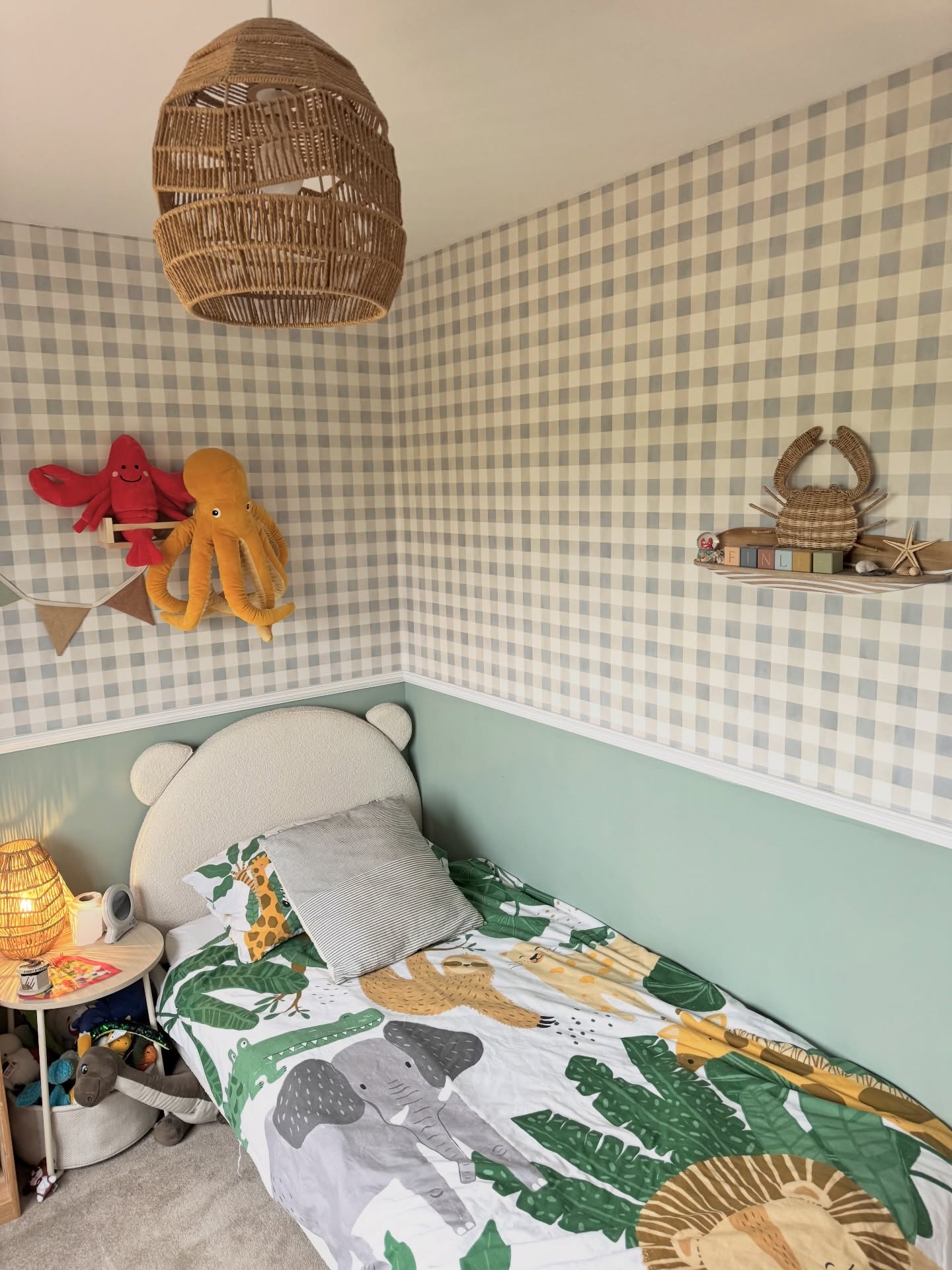 Children's bedroom with animal bedding, gingham wallpaper, and a bear-shaped headboard.