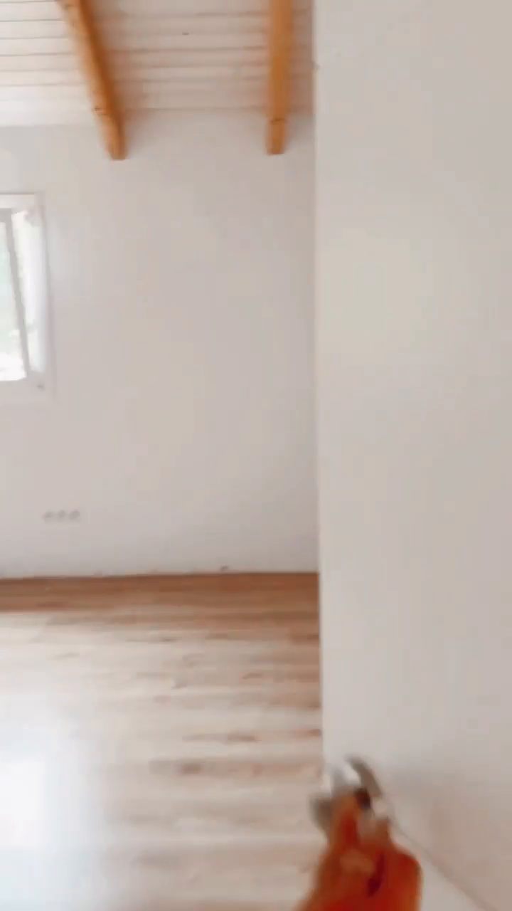 Bright, empty room with hardwood floors, white walls, and exposed wood ceiling beams.