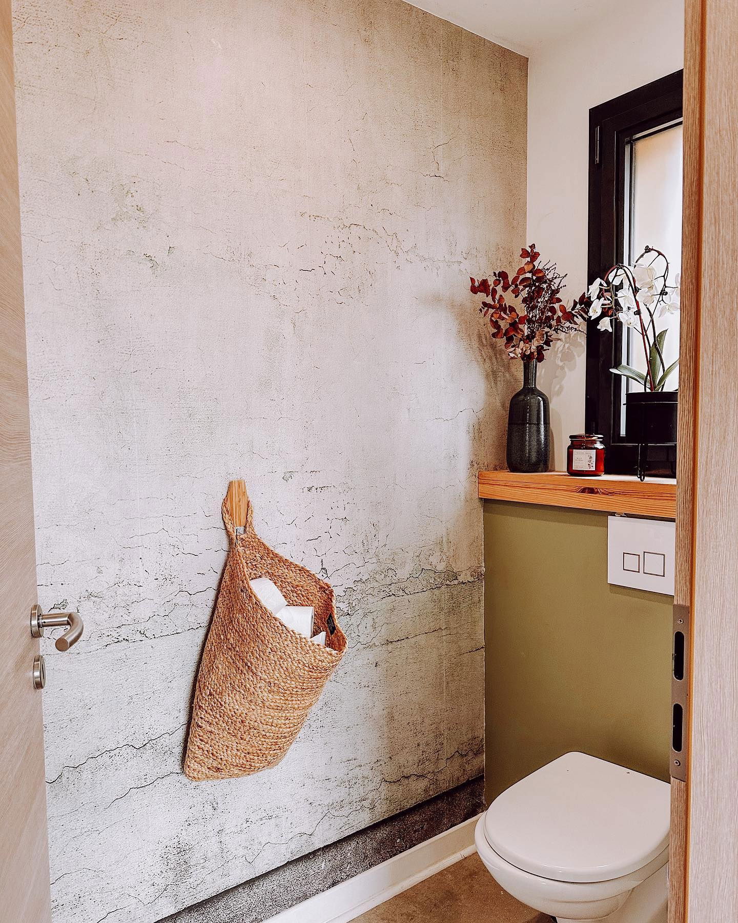 Bathroom with textured wall, woven basket holding toilet paper, and toilet.