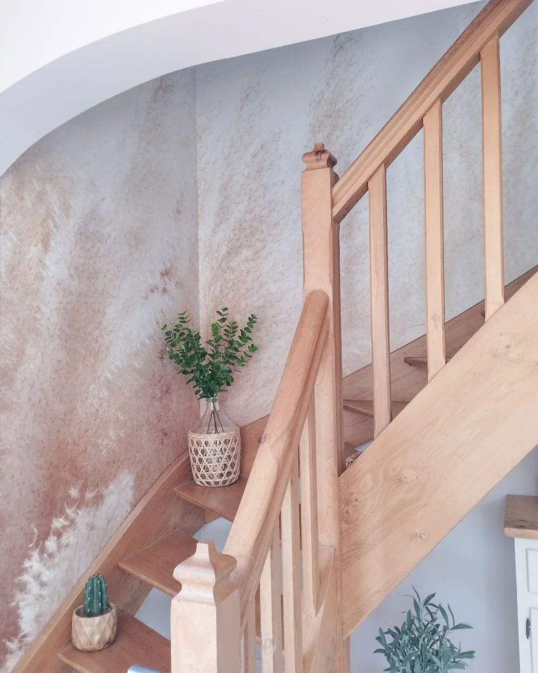 Escalera de madera con plantas en los escalones, contra una pared texturizada.