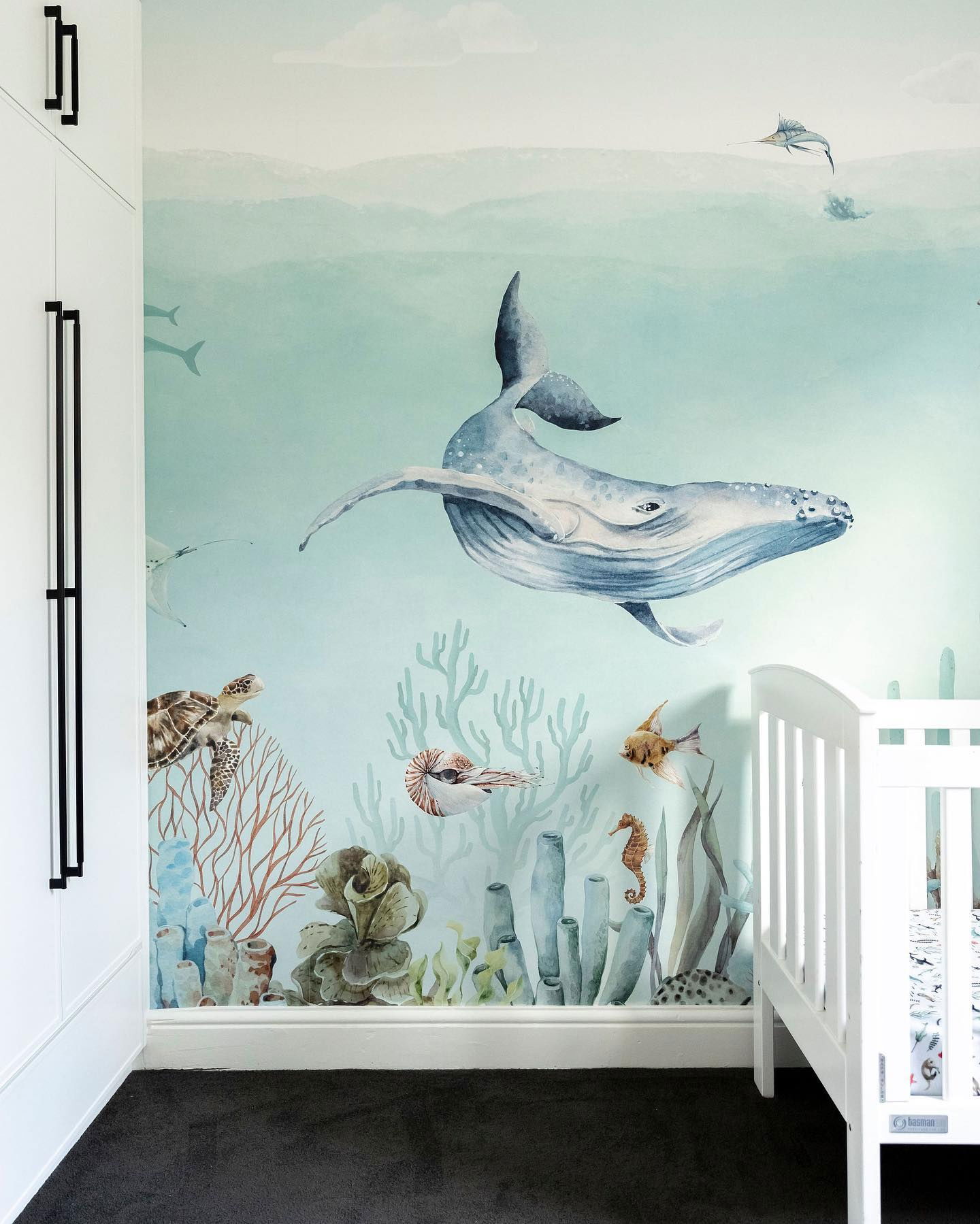 Nursery with ocean-themed wallpaper featuring a whale, turtle, and coral.