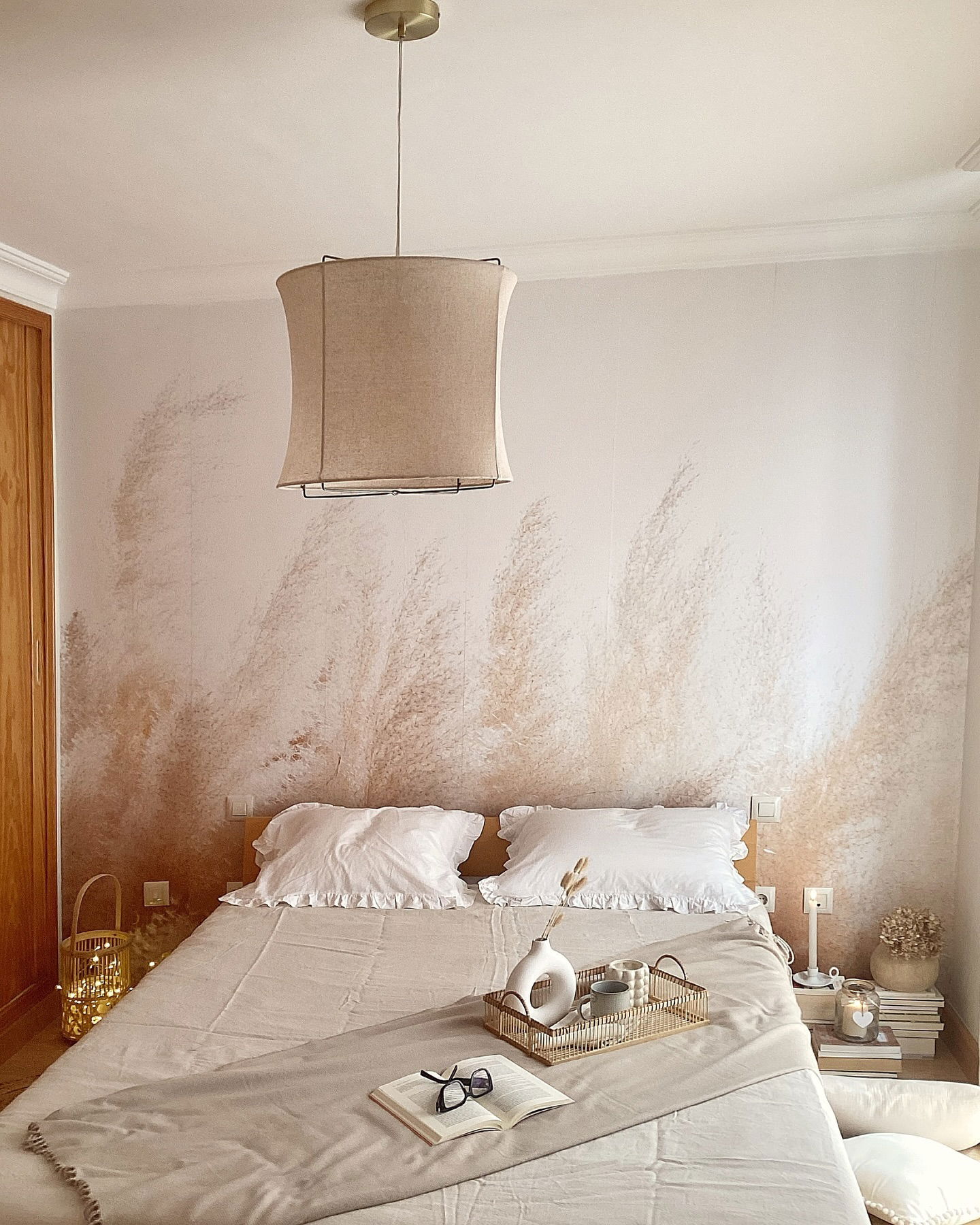 Bedroom with beige linen bedding, white ruffled pillows, and a decorative wall mural.