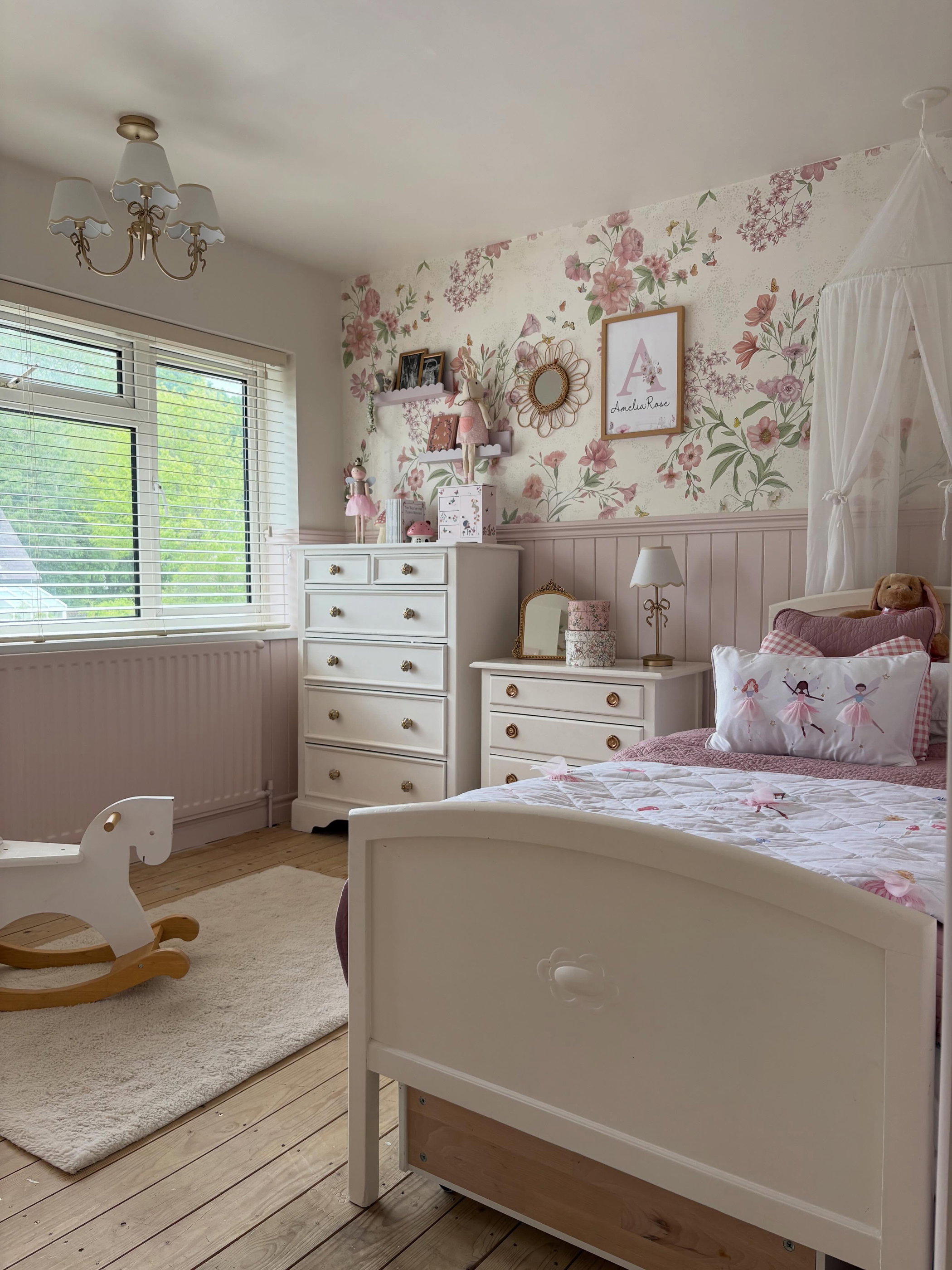 Child's bedroom with floral wallpaper, white bed, dresser, and rocking horse.