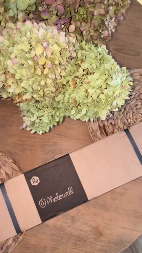Photowall package on a wooden table with dried hydrangeas.