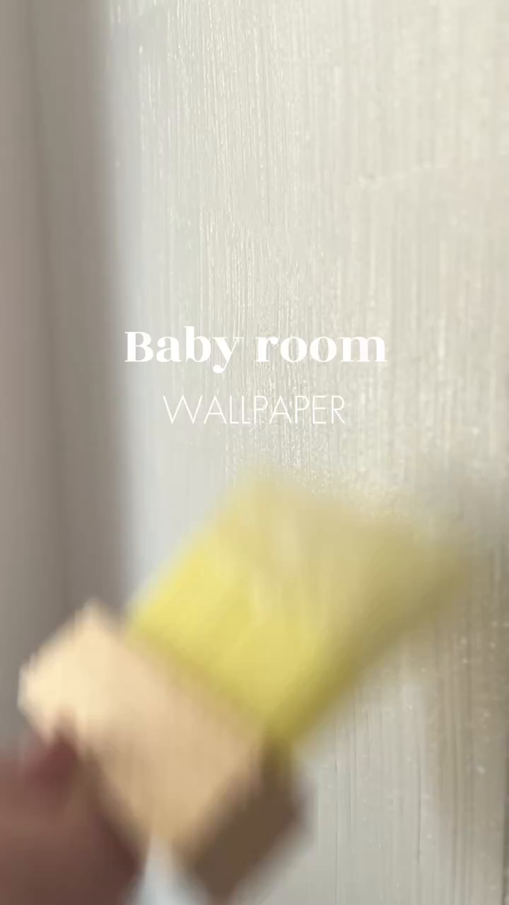 Blurred image of a yellow sponge applying wallpaper to a wall.