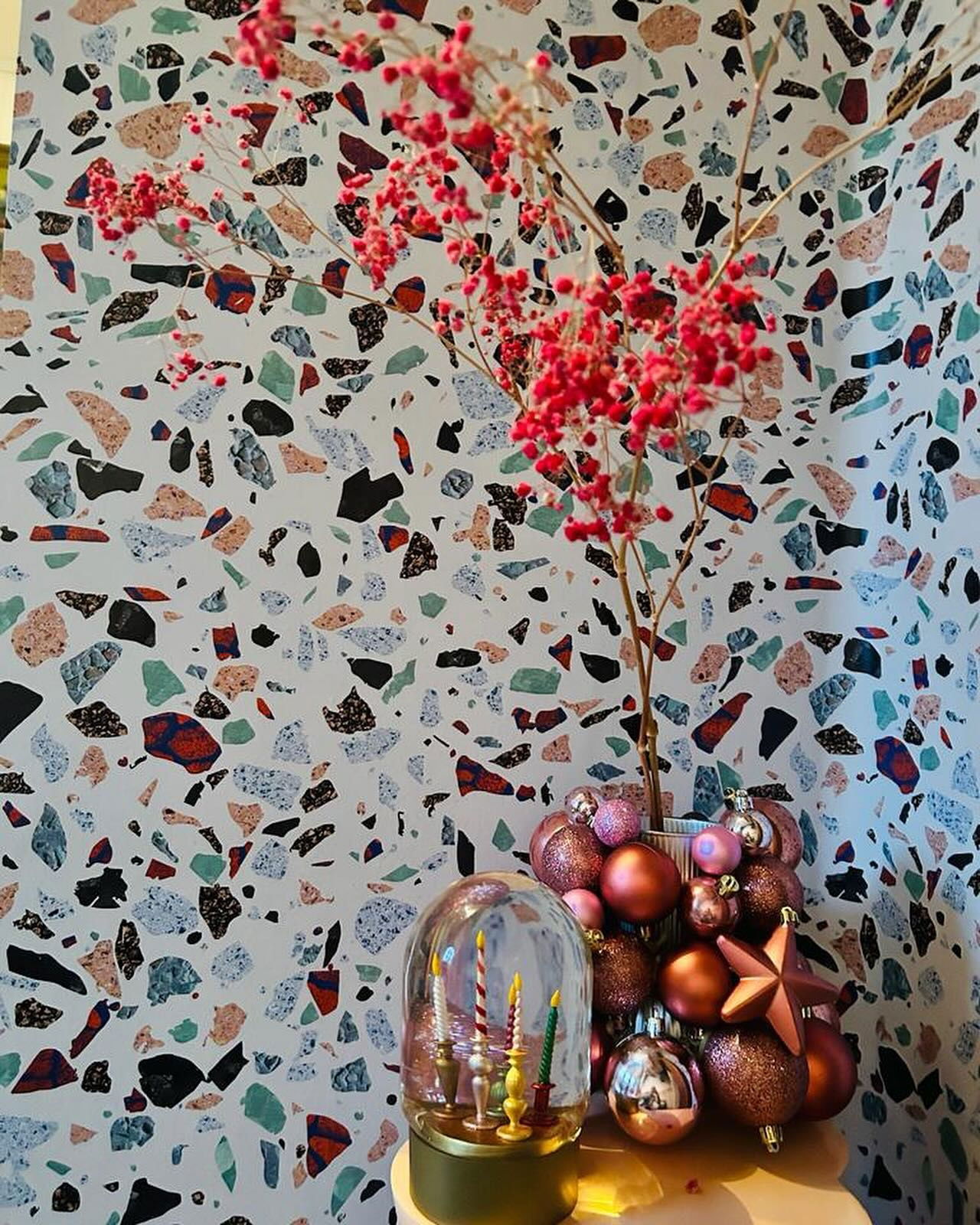 Festive holiday display with red berries, ornaments, and a candle snow globe.