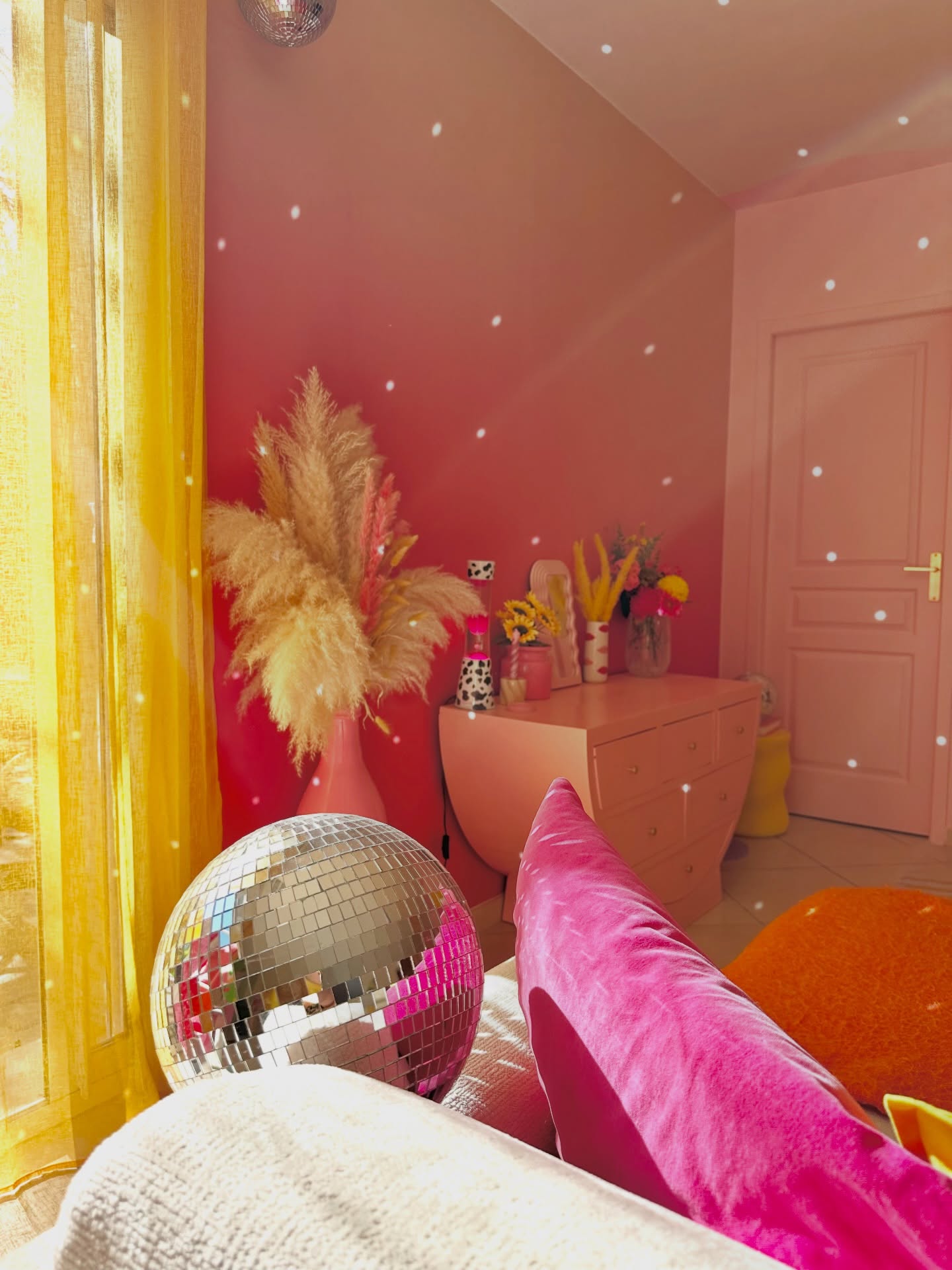 Pink room with disco ball, Pampas grass, and yellow curtains.