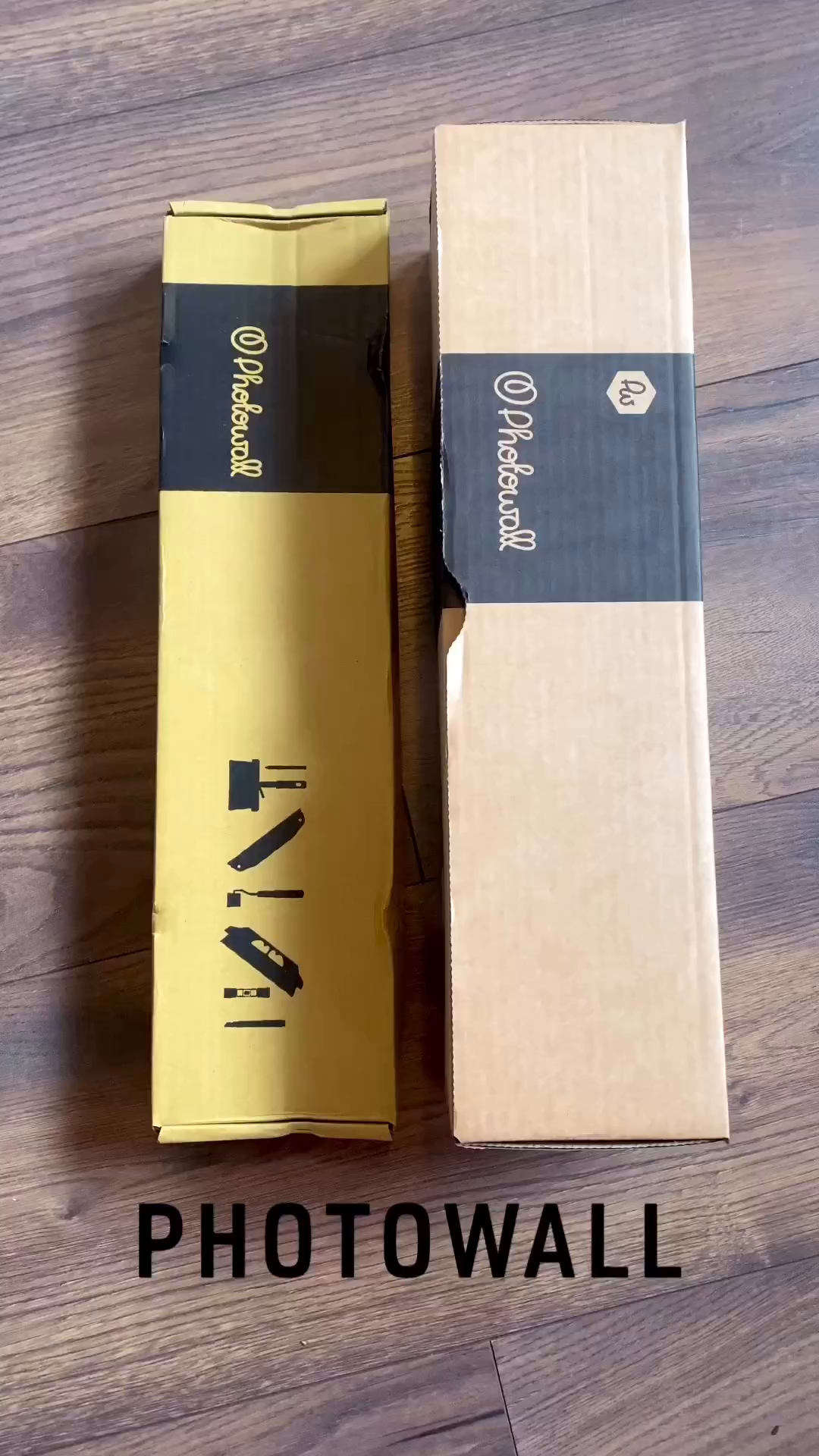 Two Photowall boxes, one yellow and one cardboard, on a wood floor.