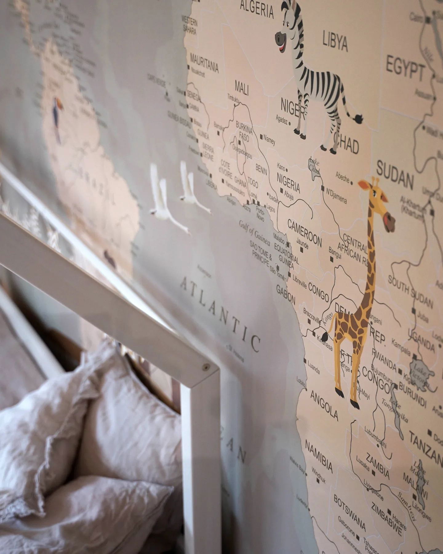 Primo piano di una mappa del mondo con illustrazioni di animali, cuscini e una struttura del letto.
