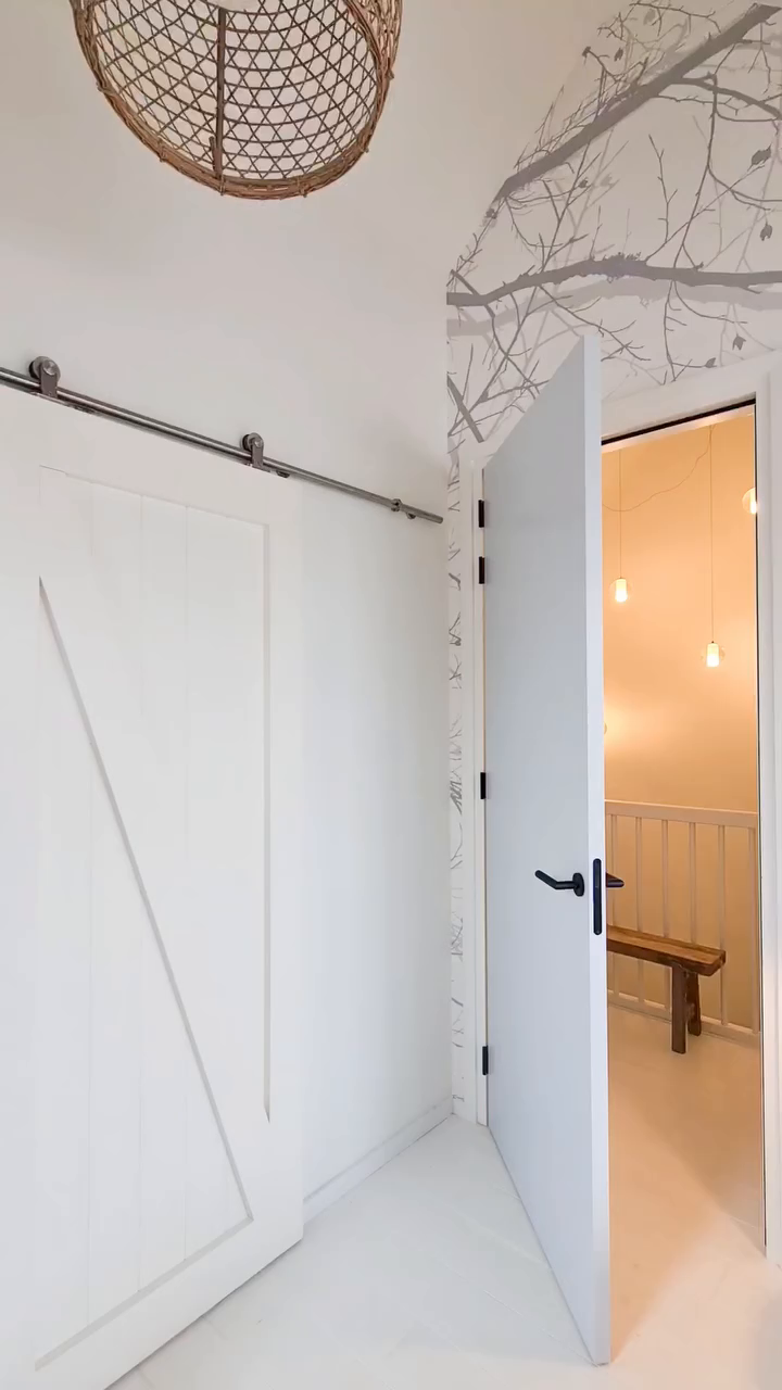 Hallway with white barn door, open doorway, and woven pendant light.