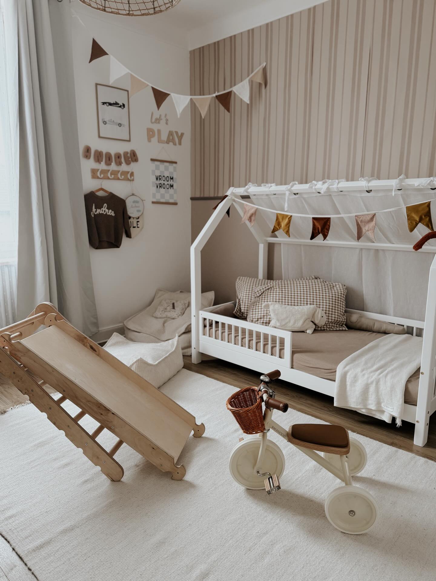 A child's bedroom with a wooden slide, house bed, and tricycle.