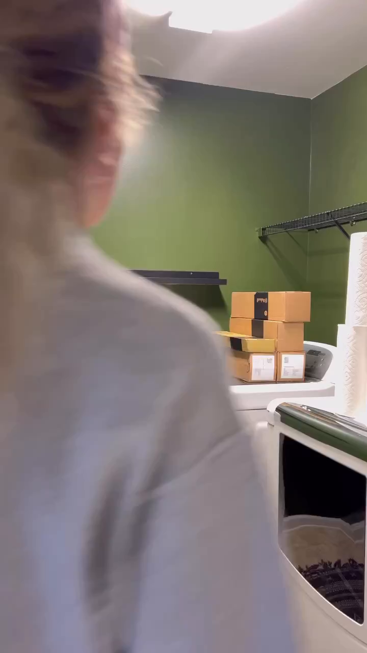 Laundry room with stacked boxes on a washing machine, and a person in the foreground.